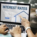 a couple looks at interest rates online to determine if they should refinance their mortgage