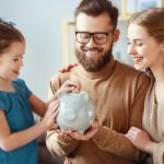 parents teaching their child good financial habits by saving money in a piggy bank
