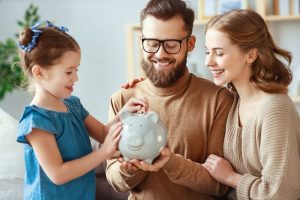 parents teaching their child good financial habits by saving money in a piggy bank