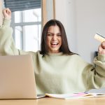 a young woman excitedly holding the no credit credit card she was approved for