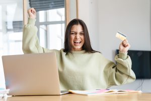 a young woman excitedly holding the no credit credit card she was approved for