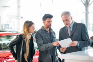 a couple talks with a salesman at the dealership about how to finance a used car