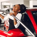 a woman smiles joyfully in her new vehicle after a pleasant car buying experience
