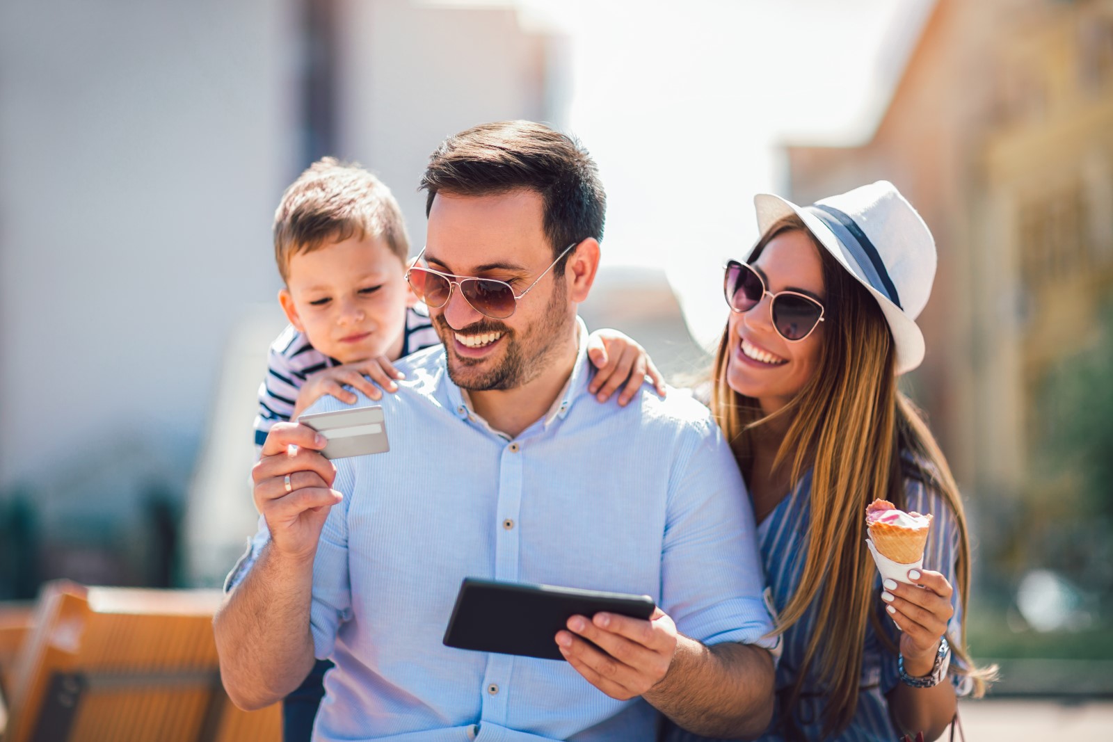 A man is using his Basic Checking Account to do a quick transaction on his phone while his wife and child look on.
