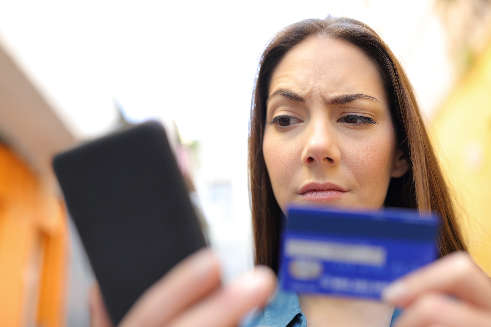 A woman suspecting that her credit card information has been compromised reads an article on her phone about how to prevent credit card fraud.