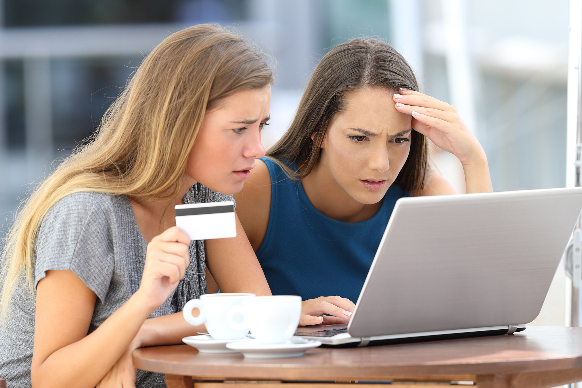 Two female friends researching identity theft recovery on a laptop.